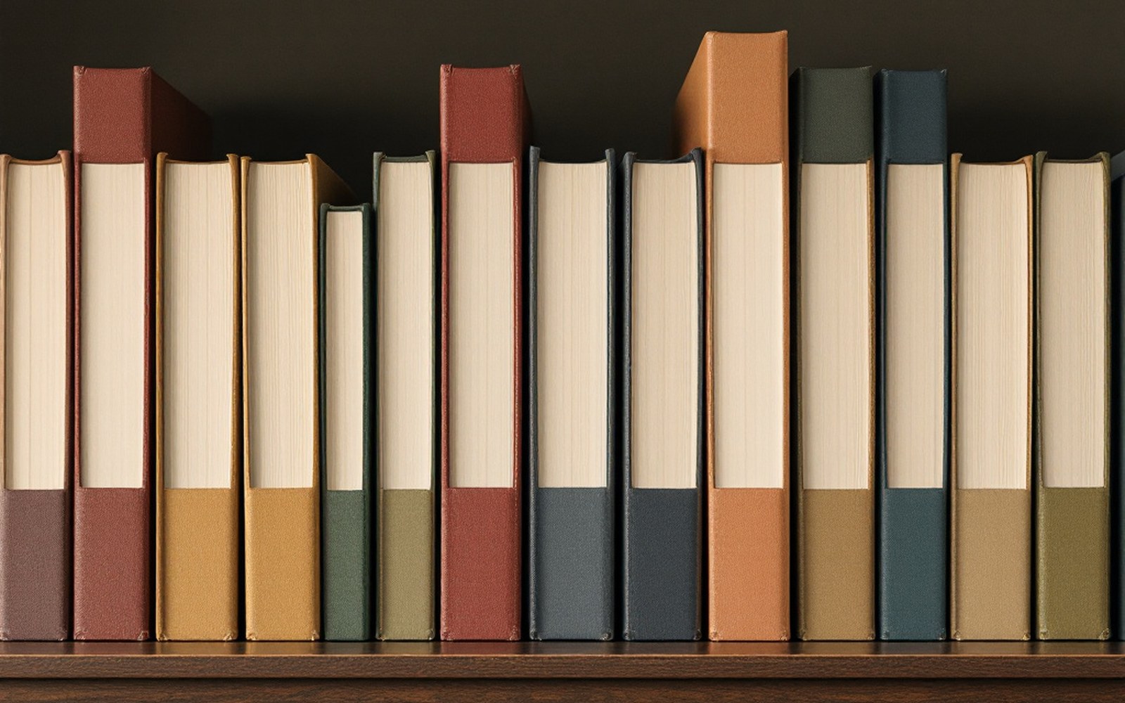 A row of uniform paperbacks with colour-banded spines standing on a shelf, seen square on